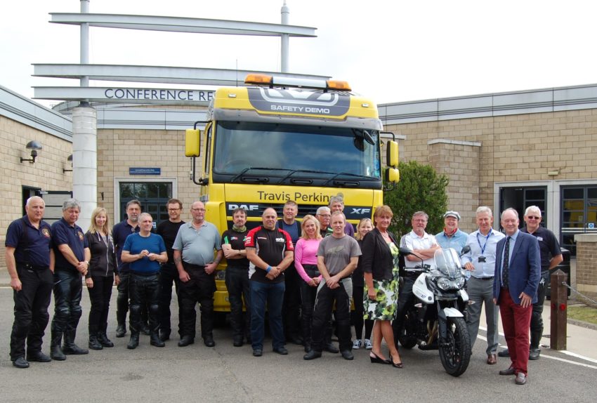 The class poses in front of a truck during the Rider Skills Day. Participants got the chance to climb into the cab to the limited visibility the driver would have of bikers.