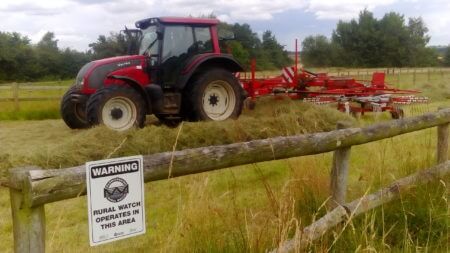 A tractor passes by a Warwickshire Rural Watch sign