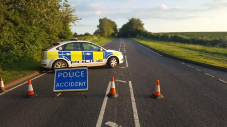 A police car sits across a closed road with 'Police accident' signs