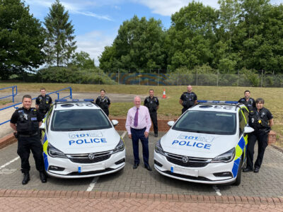 Warwickshire Police and Crime Commissioner Philip Seccombe stands between two police cars with members of the new Vehicle Crime Team at Greys Mallory.