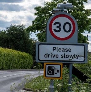 A road sign saying 'please drive slowly'