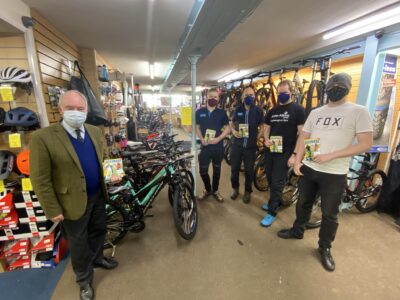 Philip Seccombe handing over copies of the Ultimate Guide to Cycling to staff at John Atkins Cycles in Leamington Spa