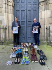 Philip Seccombe and Councillor Andy Crump stand behind 34 pairs of shoes.