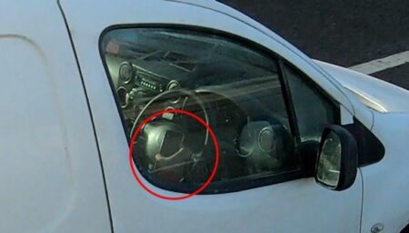 A van driver uses a phone while driving