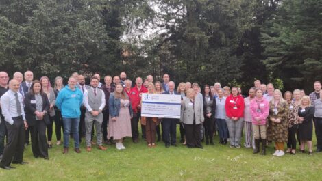 A large group of grants recipients stand with the Commissioner and a giant cheque