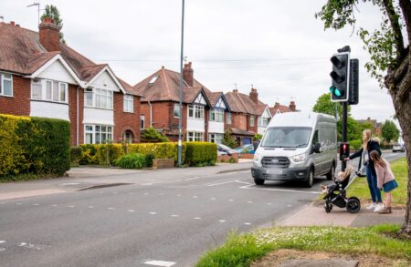 Mum with young family at pedestrian crossing as a van passes