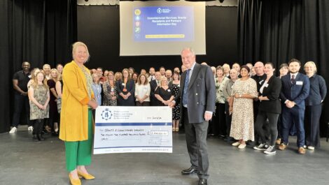 The Deputy PCC and PCC stand with a giant cheque for £2.2m in front of a group of people